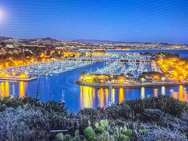 Dana Point Harbor twinkling at night with boat lights and marina glow.
