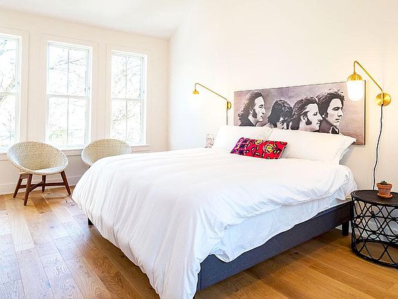 The huge open and airy master bedroom features a king bed, seating area, TV, and large windows on both side walls. There's an adjoining office nook and master bath and closet.