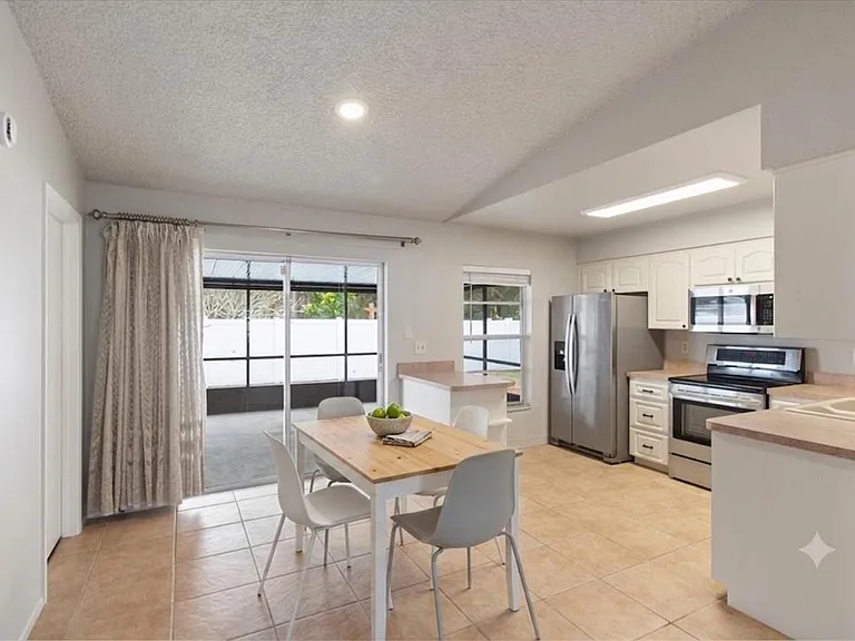 Open kitchen with ample cabinetry, stainless appliances, and a dining nook with sliding doors to the patio.