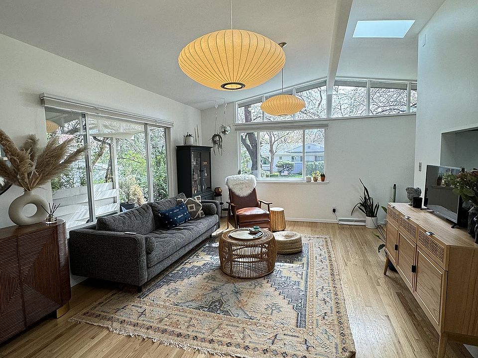 Living room with two skylights, vaulted ceilings, and hardwood floors.