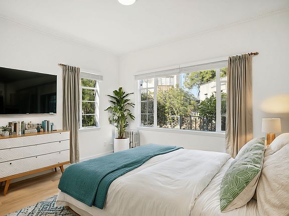 Bedroom with a large bed, comforter, a large window allows natural light to filter into the room