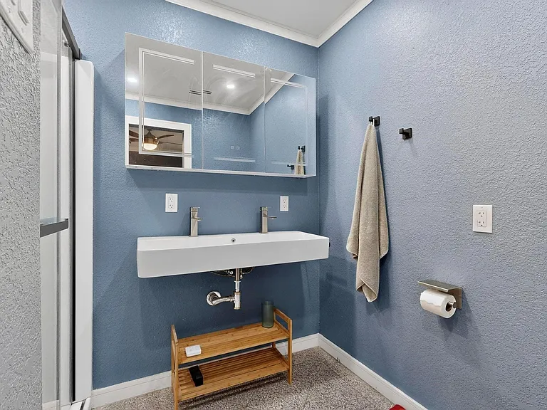 A bright primary bathroom with a dual sink and a wide mirror above it