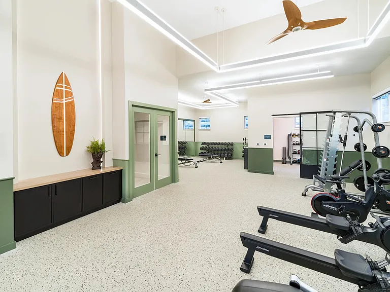 With airy ceilings and sleek coastal design, the fitness center at Modera South Shore features premium equipment_including rowers for a full-body workout.