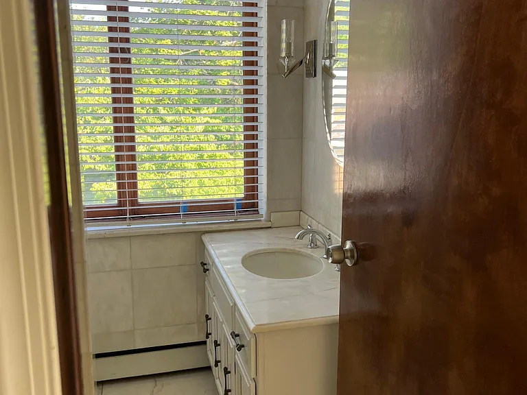 entry level full white marble bathroom near side door entrance and family room