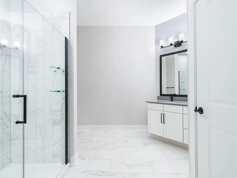 Designer bathrooms with quartz countertops and frameless glass showers.