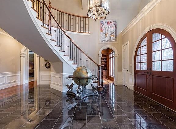 Gorgeous foyer with marble floors and dramatic staircase.  Notice the beautiful arched doors.