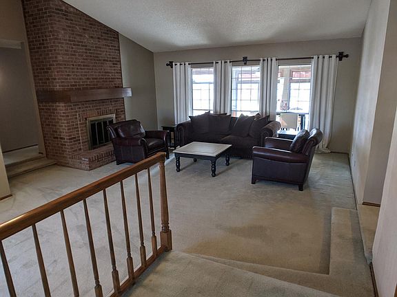 Entry leading to an open and spacious living room with vaulted ceilings and wood-burning fireplace.