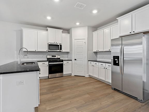 Chef-ready kitchen with designer finishes, like black countertops and white cabinets.