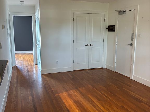 Living room with front door, entry closet, and hallway to bedroom.