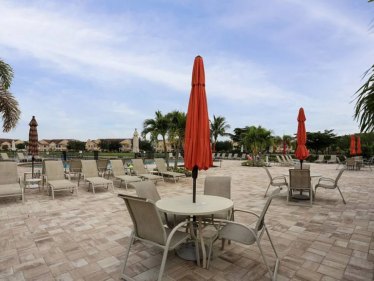 Community pool area w/ loungers, tables, chairs and umbrellas