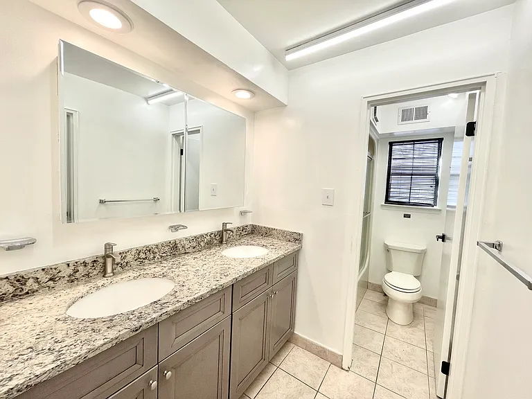 Large double granite top vanity with a separate door into the shower & toilet area