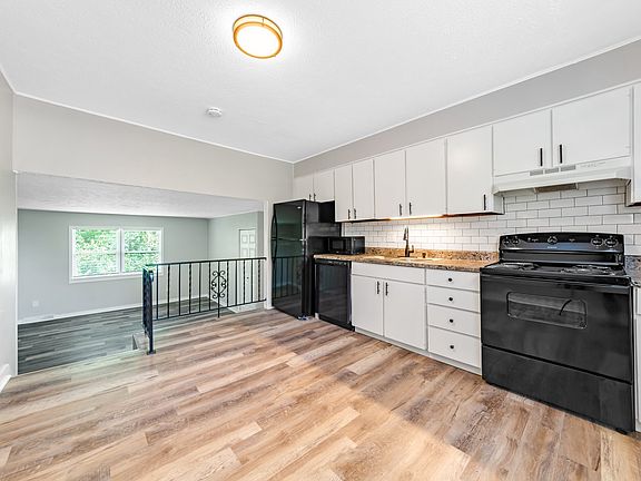 Brand new kitchen, including new black range, washing machine, and refrigerator.
