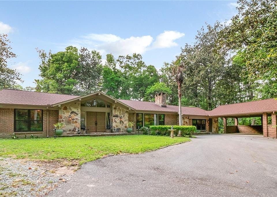 Ranch-style house featuring a chimney, aphalt driveway, stone siding, a front yard, and brick siding