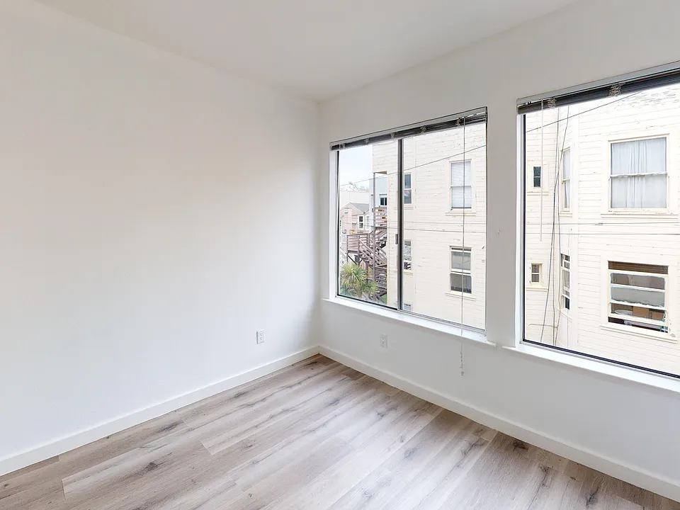 Spacious room with wood-like flooring and a large window offering natural light