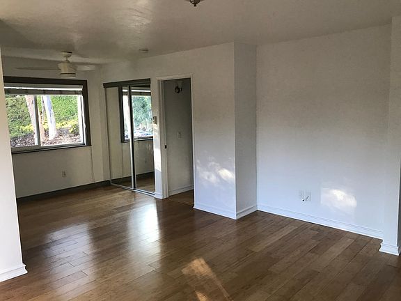 Living room/dining room area with large bright window and bamboo floors