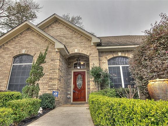 Beautifully landscaped walkway with fountain leads you to a rich wood and glass front door.