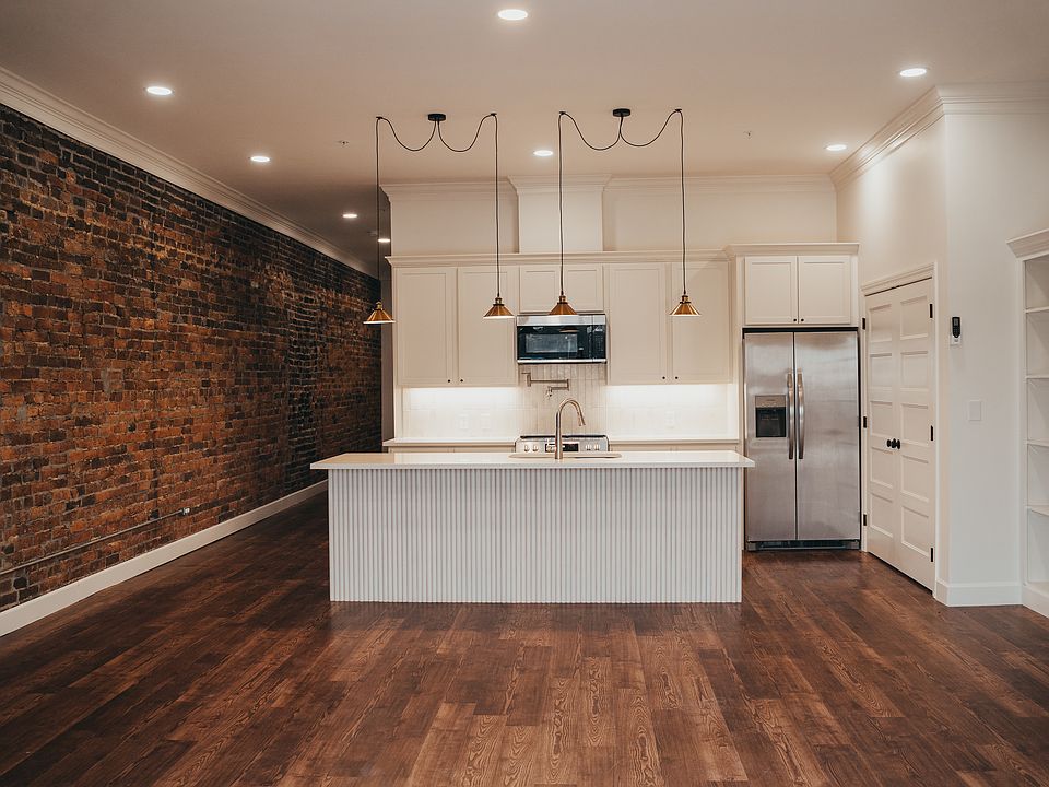 Kitchen and Living Room with exposed brick wall and laundry closet off of kitchen.