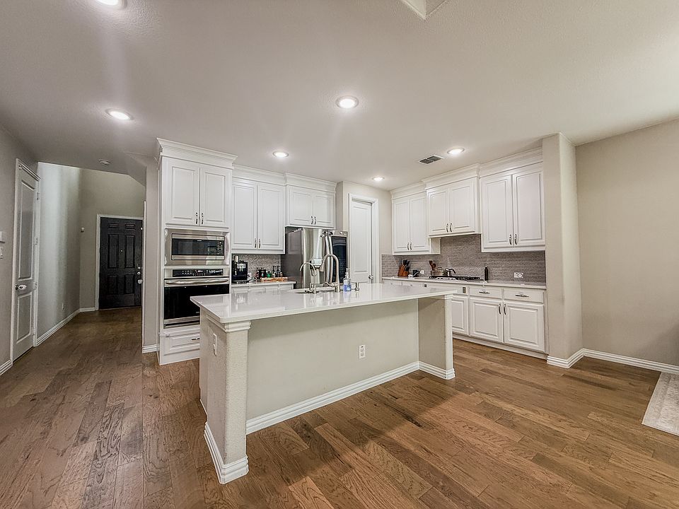 Sophisticated kitchen offers massive island bar for family feast, bar stool seating, floor-to-ceiling cabinetry, and widened walkway entracne