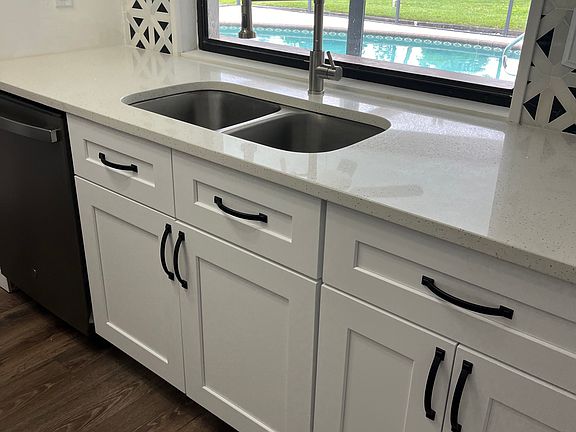 Newer kitchen with quartz countertop overlooks the pool with serving window to the tiki bar.