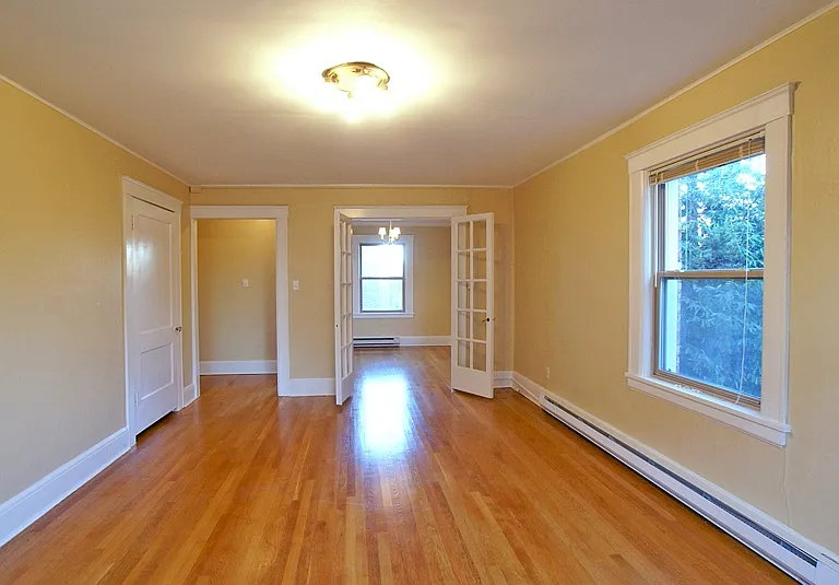 Large bright corner living room with hardwood floors, high ceilings, plenty of light