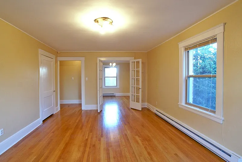 Large bright corner living room with hardwood floors, high ceilings, plenty of light
