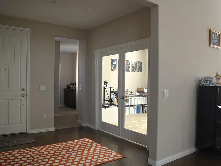 Study Room with double French doors viewed from kitchen area. The photo also shows the main entrance door from inside, and hall way to the west wing area of the house