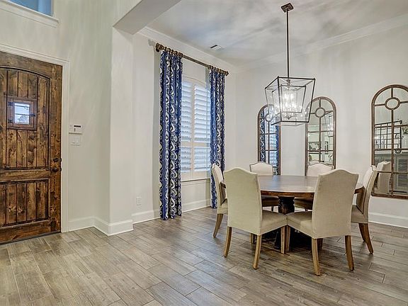 As you enter, the elegant formal dining room is immediately to the left. Gorgeous wood-look tile floors extend through this space, as does soft neutral paint and thick crown molding. A beautiful chandelier stands over the dining room table and planta