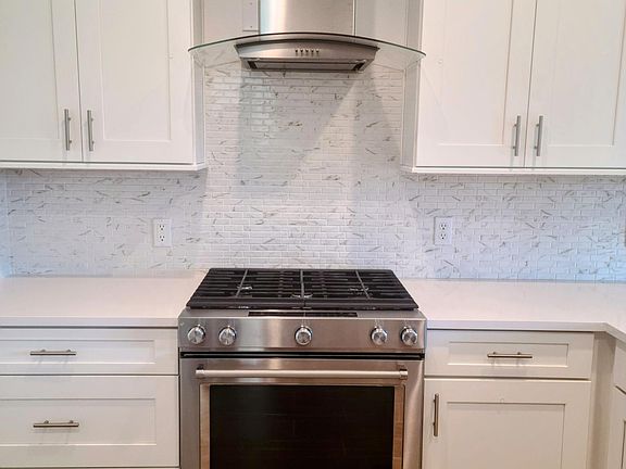 Kitchen featuring high-end KitchenAid gas range and hood