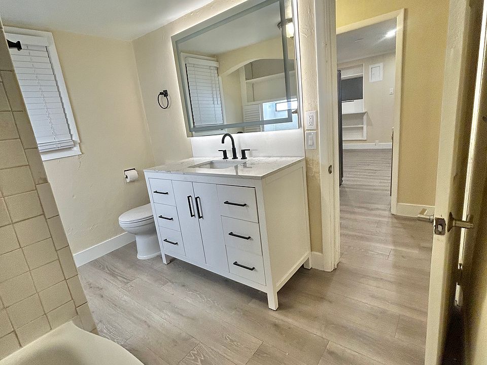 Well lit bathroom including backlit mirror, powder deskset, vanity with tons of storage and new bath fixtures