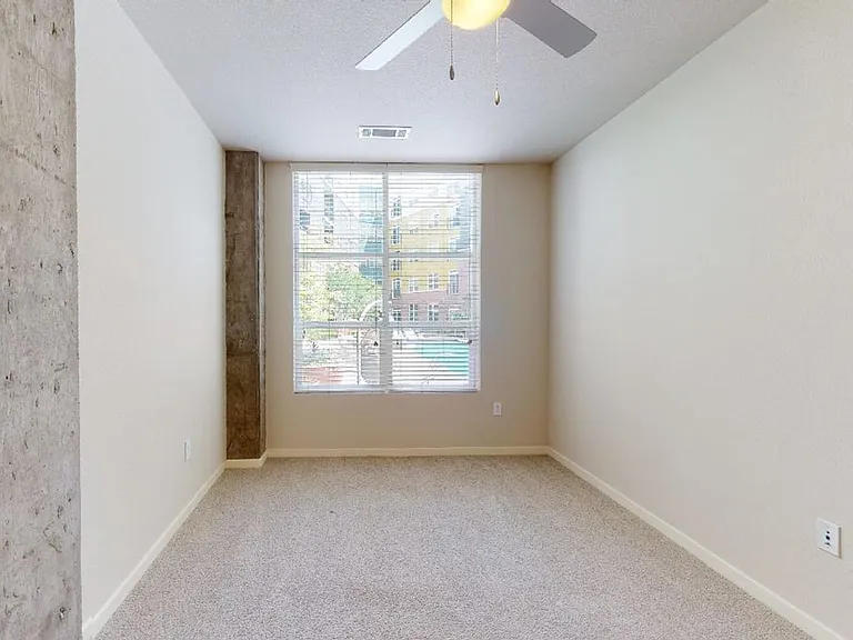 Spacious apartment bedroom with plush carpet flooring.