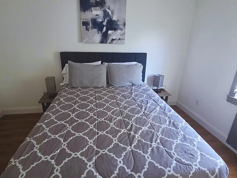 Bright bedroom with a queen bed, premium linens and cozy bedside lamps.