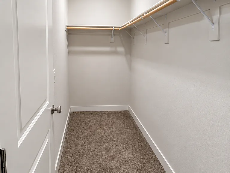 Spacious walk_in closet with fresh white walls, dual hanging rods for easy organization, soft carpet flooring, and bright recessed lighting for a clean, functional storage space.