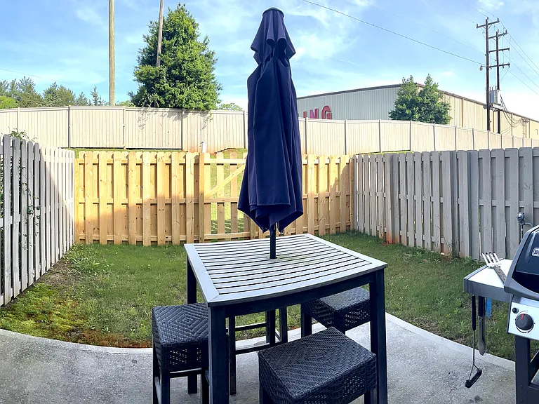 Fenced-in back yard with privacy fence, outdoor seating, and grill.