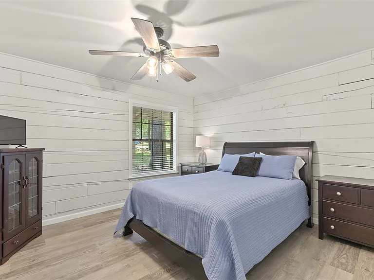 Interior room featuring white horizontal plank walls and wood-finish flooring