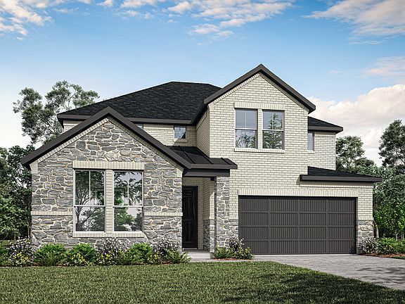 A two-story house with a stone exterior, a black roof, and a garage door stands in a grassy area sur