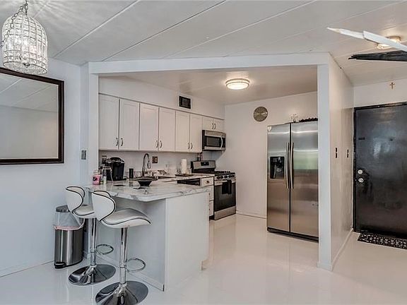 THE DARK DOORS AND WHITE POLISHED PORCELAIN FLOORS PLAY WELL WITH ONE ANOTHER AS YOU LOOK INTO THE KITCHEN AREA