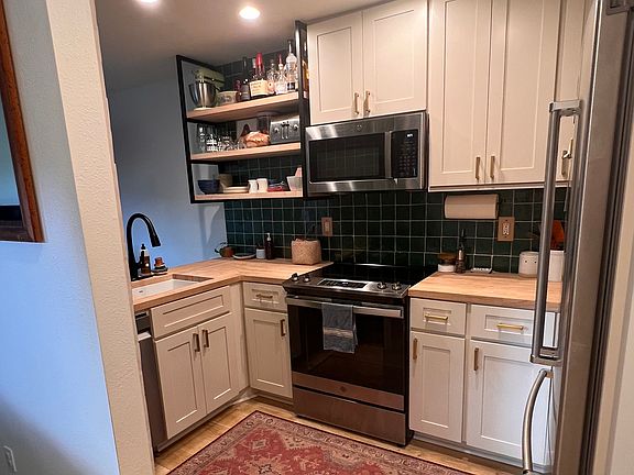 Fully renovated kitchen with all new appliances (including dishwasher!). New white shaker cabinets paired with handmade, emerald green zellige tile and gold hardware.