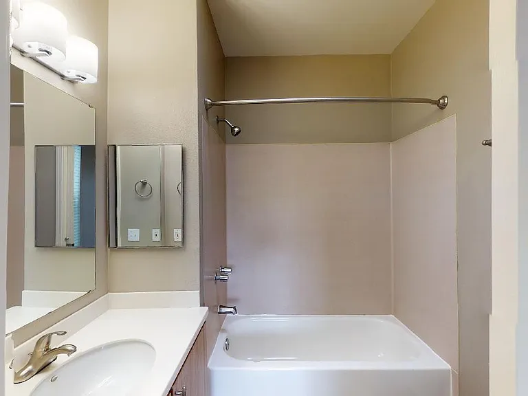 Apartment bathroom with soaking tub and wood-style flooring.
