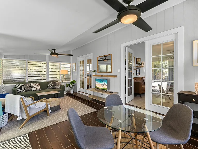 Enclosed lanai adds additional living space, a futon sofa, chair, TV, small dining set for 3-4, and a desk. Two large fans and lots of windows keep this area cool.