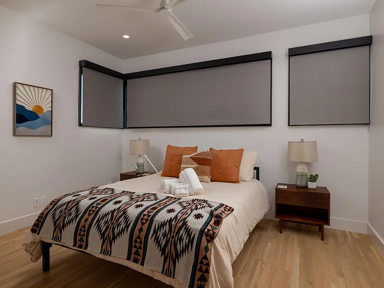 Bedroom 2 features a queen bed and windows on two sides, with room-darkening shades for restful sleep and added privacy.