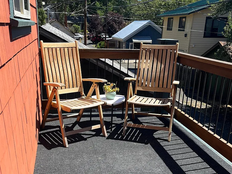 Large out door deck with teak chairs and small gas grill.