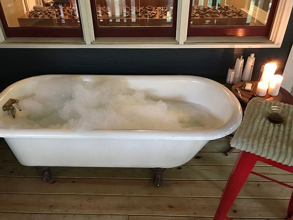 clawfoot bathtub on porch (with curtain)