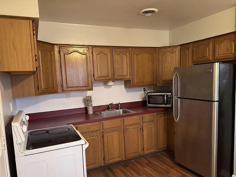 Functional kitchen with ample wood cabinetry, laminate counters, stainless refrigerator, and a convenient sink workspace.