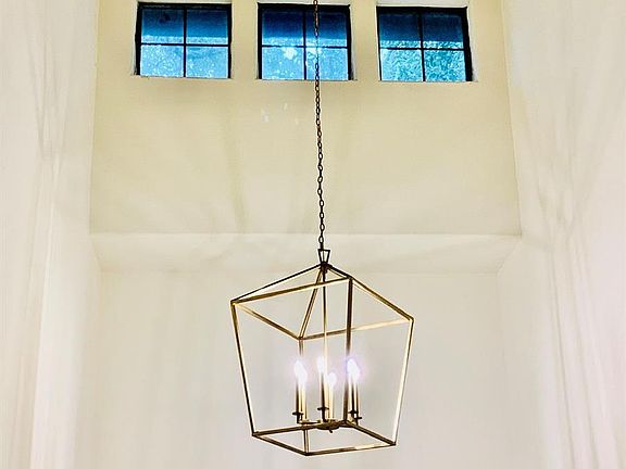 The two-story Foyer is lit with the gold chandelier and highlighted by clerestory windows.