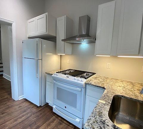 Newly renovated kitchen with gas stove, recessed lighting, and white cabinetry