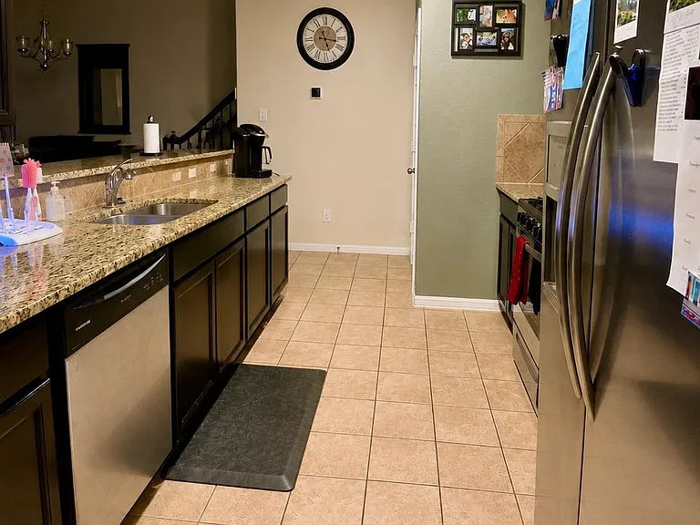 Galley-style kitchen with granite counters, stainless appliances, tile flooring, and ample cabinet storage for daily use.