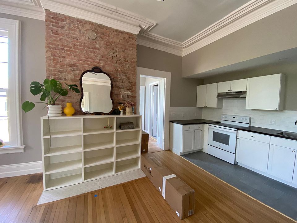 Built in shelves, exposed brick - view of kitchen, doorway leads to bedroom