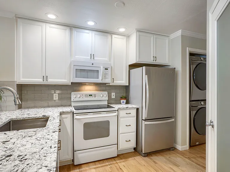 Kitchen & In-Unit Laundry _ Modern appliances, including a Whirlpool refrigerator, range, and microwave, blend seamlessly with the kitchen's updated finishes and timeless design. In-unit Samsung smart stackable washer and dryer provide added convenience.