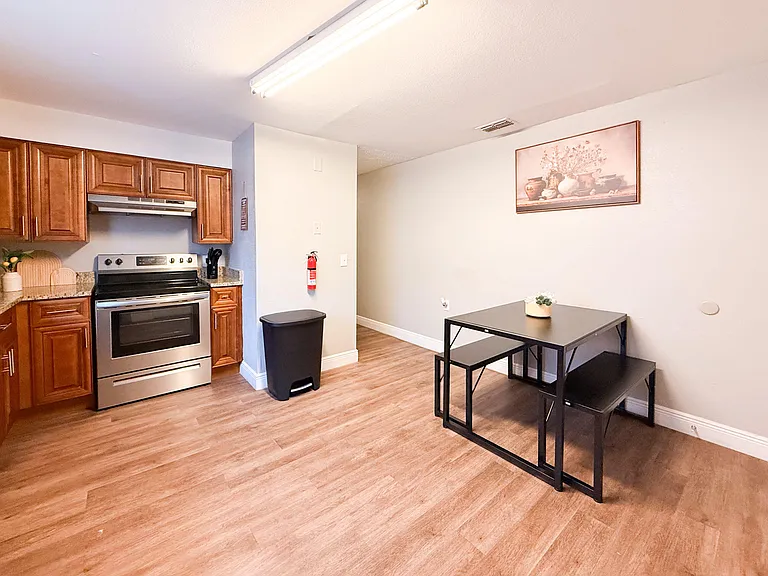 Kitchen with wood cabinetry, electric range, and adjacent dining nook with table seating on durable plank flooring.