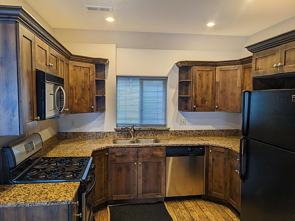 Kitchen with stove, microwave, dishwasher, and refridgerator/freezer. Window leads to back yard